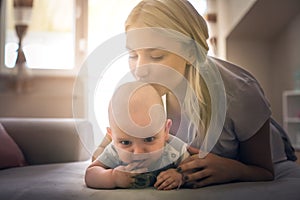 Happy mother on bed with her little baby boy at home.