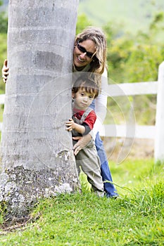 Happy mother and boy hugging a tree
