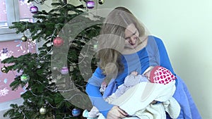 Happy mother breastfeed feed infant baby near Christmas tree