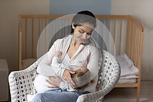 Happy mother breastfeed newborn baby daughter in chair