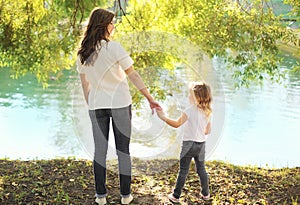 Happy mother and child daughter holding hands together in summer