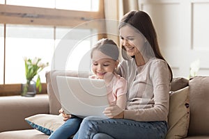 Happy mother and child daughter use laptop computer at home