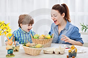 Happy mother and child looking at easter colored eggs and smiling