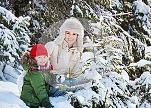 Happy mother and child outdoors among snowy spruces