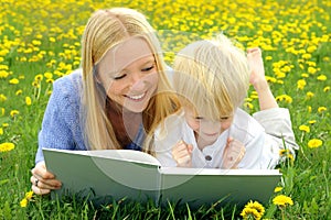 Feliz madre a lectura un libro afuera en prado 