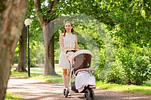 Happy mother with child in stroller at summer park