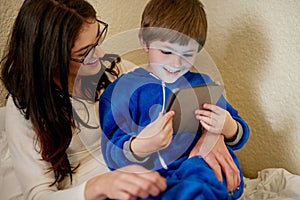 Happy mother, child and tablet in home bedroom for learning, education and storytelling with boy. Mom, kid and digital