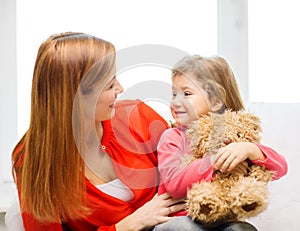 Happy mother and child with teddy bear at home