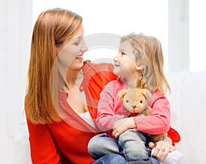 Happy mother and child with teddy bear at home