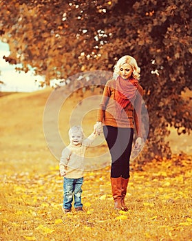 Happy mother and child walking together in autumn park
