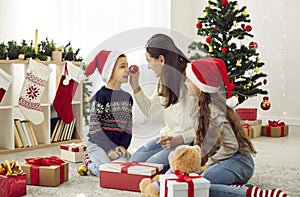 Happy mother and children having fun with festive ornaments on Christmas Day at home