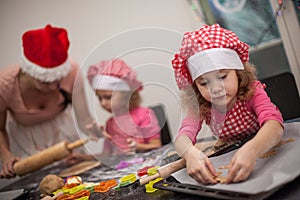 Happy mother and children identical twin daughters bake kneading dough in the kitchen,casual lifestyle photo in real life interior