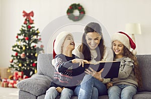 Happy mother and children reading funny books and having fun on Christmas holidays