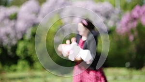 Happy mother and cute baby-girl playing together in a park against beautiful flowers.