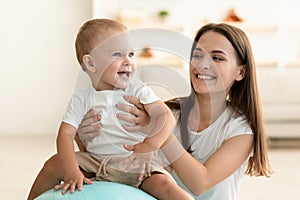 Happy Mother And Cute Little Baby Playing With Fitness Ball At Home