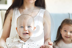 Happy mother and cute little kids spending time together and smiling at camera