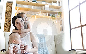 Happy mother and cute little kids spending time together and smiling at camera