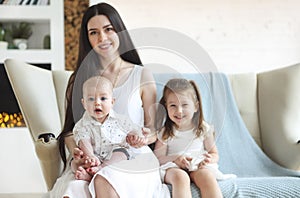 Happy mother and cute little kids spending time together and smiling at camera