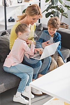 happy mother with cute smiling children using laptop together