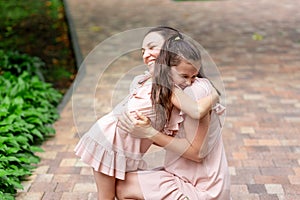 Happy mother and daughter 5-6 years old walk in the Park in the summer, mother hugs her daughter, the concept of a happy family,