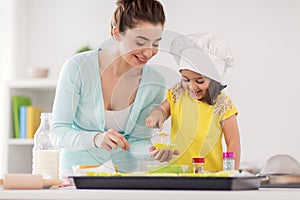 Happy mother and daughter baking cupcakes at home