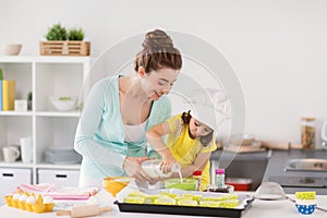 Happy mother and daughter baking cupcakes at home