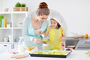 Happy mother and daughter baking cupcakes at home