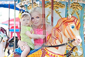 Happy mother and daughter on carousel