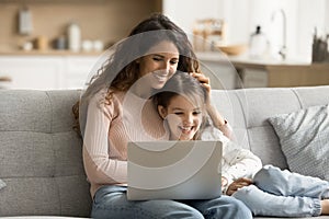 Happy mother and daughter child enjoying family leisure at laptop