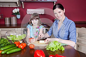 Happy mother and daughter enjoy making and having healthy meal together at their kitchen.