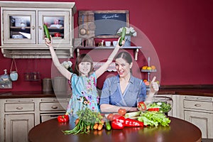 Happy mother and daughter enjoy making and having healthy meal together at their kitchen.