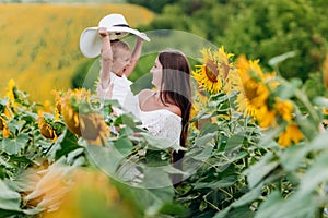 Happy mother with the daughter in the field with sunflowers. mom and baby girl having fun outdoors. family concept