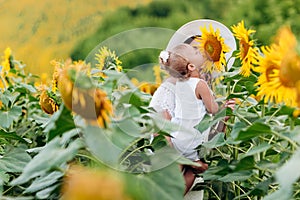 Happy mother with the daughter in the field with sunflowers. mom and baby girl having fun outdoors. family concept