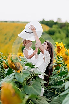 Happy mother with the daughter in the field with sunflowers. mom and baby girl having fun outdoors. family concept