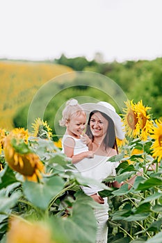 Happy mother with the daughter in the field with sunflowers. mom and baby girl having fun outdoors. family concept. selective