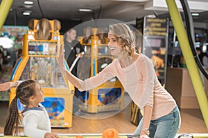 happy mother and daughter giving high five while playing air