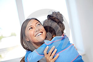 Happy mother and daughter hugging at home