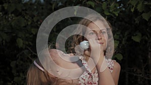 A happy mother and daughter inflate soap bubbles. Family in a city park on a picnic on a warm evening at sunset.