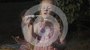 A happy mother and daughter inflate soap bubbles. Family in a city park on a picnic on a warm evening at sunset.