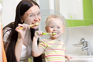 Happy mother and daughter kid girl brushing teeth
