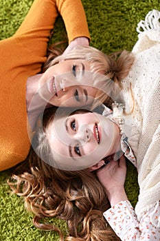 Portrait of mother with daughter lying on green carpet photo
