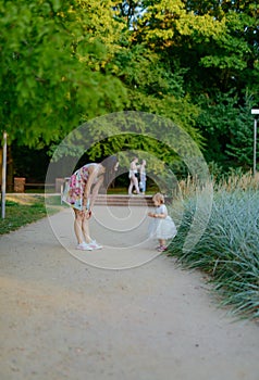 Happy mother and daughter in the park. Beauty nature scene with family outdoor lifestyle. Happy family resting together on the