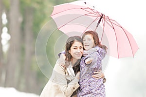 Happy mother and daughter in park in rain.