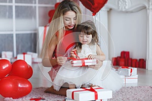 Happy mother and daughter parses gifts on Valentine`s Day