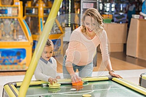 happy mother and daughter playing air hockey together