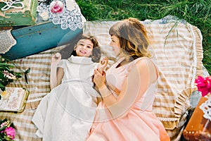 Happy mother and daughter playing and smiling while lying on a blanket in the summer