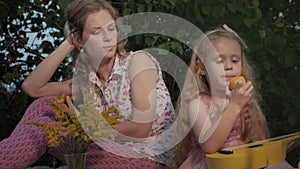 A happy mother and daughter are playing on the ukulele. Family in a city park on a picnic on a warm evening at sunset.