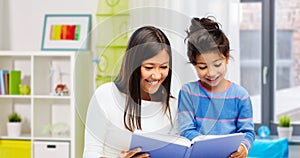 happy mother and daughter reading book at home