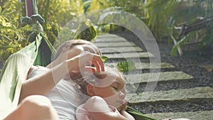 Happy mother and daughter relaxing together in a hammock at garden in summer day