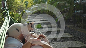 Happy mother and daughter relaxing together in a hammock at garden in summer day